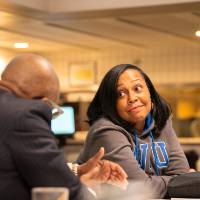 Woman in conversation with other event guest sitting at her table